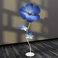 Floral Art Installation Featuring Blue Flower Metal Stem Decorative Leaves Shadow Effect On Wooden Floor