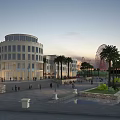 Evening Commercial Street Scene with Circular Building Palm Trees Water Feature and Ferris Wheel