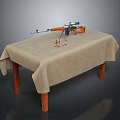 Rifle with orange components on wooden table with beige tablecloth and bullet casings nearby