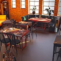 Cozy Café Interior With Brick Walls Large Windows Wooden Tables Black Chairs And Potted Plants