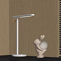 White Illuminated Table Lamp On Wooden Table With Rabbit Shaped Decor And Blinds