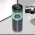 Black Cylindrical Electronic Appliance With Blue Circular Light And Grilled Top On Desktop