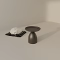 Black Side Table with Round Tray and Conical Base Near White Plush on Black Mat