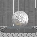 Silver Spherical Metallic Sculpture With Orange Red Textured Surface On Black Pedestal Against Gray Wall