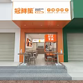 Fresh Grocery Shop Storefront with Orange Signage Green Walls White Roller Shutters and Outdoor Seating