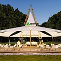 Large White Camel Brand Outdoor Tent With Wooden Frame Green Trees And Chairs