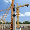Construction Site With Tower Crane Lifting Concrete Column Under Blue Sky