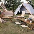 Campsite With White Tent Wooden Tables Folding Chairs And Outdoor Grass Setting