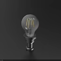 Transparent Light Bulb With Yellow Filament And Metal Base On Dark Background