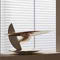 Elegant Metallic Streamlined Sculpture Artwork With Circular Base By Window Blinds