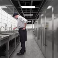 Commercial Catering Kitchen Interior With Chefs Working At Stainless Steel Worktables And Commercial Appliances