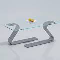 Stylish Coffee Table With Glass Top Curved Grey Metal Frame And White Plate With Yellow Fruits
