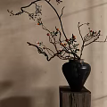 Black Vase with Branches Orange Fruits and Green Leaves on Square Base Against Beige Wall