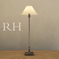 Modern Floor Lamp with Light Colored Shade Metal Pole and Square Base on Wooden Floor