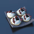 Four Delicious Cream Topped Tarts on Gray Tray With Chocolate Decorations and Black Fruits