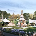 Scenic Garden Landscape With Tepees Green Lawn Trees Purple Flowers And Outdoor Seating Area