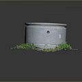 Gray Cylindrical Concrete Structure With Round Lid Surrounded By Green Grass And Dirt