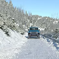 Snowy Mountain Road Scenery With Blue Jeep Snow Covered Trees Under Clear Blue Sky