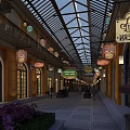 Commercial Street With Glass Roof Yellow Buildings Hanging Signs And People Walking