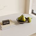 Stack of Books with Black Calendar and Green Pears on Light Round Table Near Window