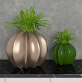 Decorative Gold And Green Vases With Green Plants Against Gray Wall And Black Marble Countertop