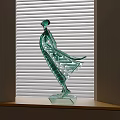 Green Glass Female Figurine With Flowing Dress For Decorative Display On Windowsill With Blinds Background
