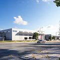 Modern Industrial Factory Exterior Design With Roadside Trees And Parked Cars Under Clear Blue Sky