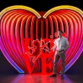 Vibrant Neon Heart Sculpture With LOVE Lettering And Cupid Design Featuring Person