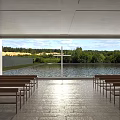 Religious Sanctuary Interior With Wooden Benches Viewing Cross Over Trees And Water