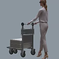Woman In Light Gray Jumpsuit Pushing Luggage Cart With Silver Checkered Suitcase