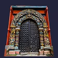 Intricately Carved Black Entrance Gate With Red Brick Walls And Colorful Decorations