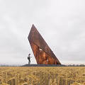 Large Rusted Triangular Metal Road Facility In Wheat Field With Person Standing Beside