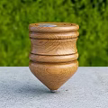 Tilted Wooden Top With Stacked Layers On Gray Tabletop And Green Plants In Background