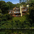 Hillside Detached Villa with Large Windows Stone Walls Greenery and Water Swans
