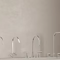 Four Sleek Silver Faucets Arranged On Countertop Against Gray Background