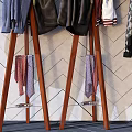 Stylish Clothes Hangers With Hanging Clothes Bags And Hats Against Geometric Patterned Wall