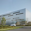 Modern Industrial Factory Building With Silver Metal Facade Rectangular Windows Lawn Trees And White Car