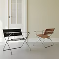 Two Modern Leisure Chairs With Black And Brown Seats And Metal Frames In Bright Interior