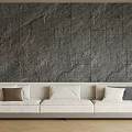 Light Colored Multi Seater Sofa With Cushions Against Dark Stone Wall And Wooden Floor