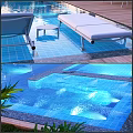 Luxury Swimming Pool Area With Lounge Chairs Sun Umbrellas Greenery Wooden Deck And Blue Lighting