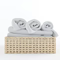 Woven Storage Basket with Rolled Light Gray Towels for Bathroom Organization