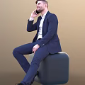 A Man In Dark Blue Suit White Shirt Sitting On Black Cube Talking On Phone