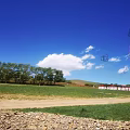 Scenic Garden Landscape with Blue Sky White Clouds Green Lawn Wooden Building and Distant Mountains