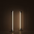 Two Modern Slim Floor Lamps with LED Light Creating Ambient Glow Against Dark Wall