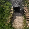 Stone Tunnel Entrance Surrounded by Lush Green Vegetation and Dirt Path