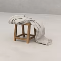 Minimalist Indoor Space With Wooden Stool And Draped Gray Blanket In Neutral Tones