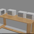 Four White Microwaves Placed On Wooden Long Table With Light Colored Wall Background