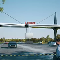 Modern Commercial Entrance Gate With Red LOGO And Support Structures Near Vehicles And Trees