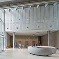 Curved Reception Desk in Modern Lobby with Glass Doors High Ceiling and Metal Walls