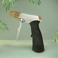Handheld Household Tool With Black Handle Silver Metal And Wooden Nozzle Against Green Leaves Background